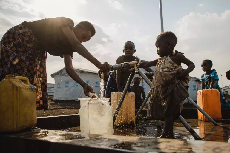 Parent and children filling water cans