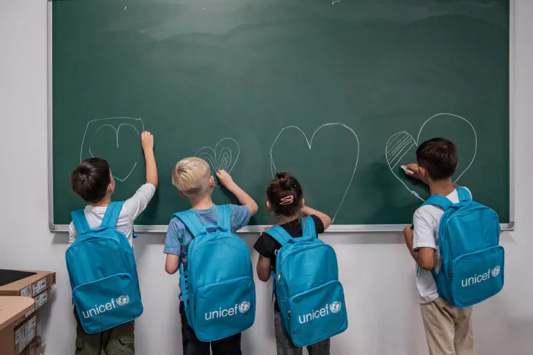 Children in school drawing hearts on the blackboard