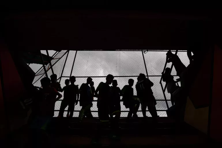 Silhouettes of children next to a railing 