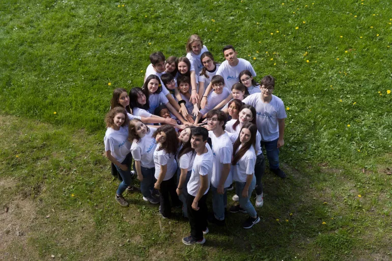 A group of adolescents are seen from above joining hands in solidarity.