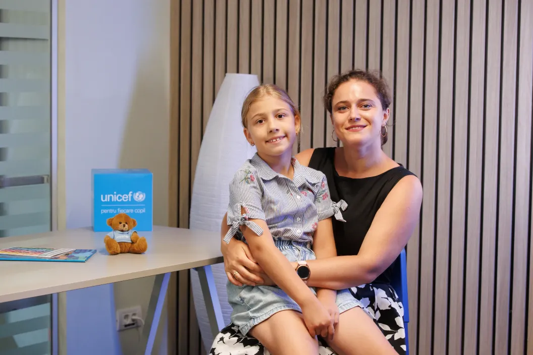 Mother and her daughter posing for a photo while being seated on a chair.