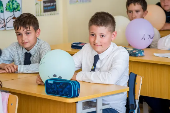 Elevi z&acirc;mbind &icirc;n băncile lor din sala de clasă din școală.