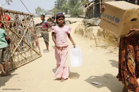 A young girl carries collapsible jerry cans that were distributed in a UNICEF hygiene kit
