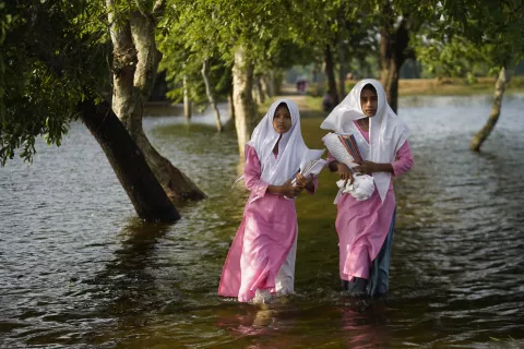Girls wading through floodwaters on the way to school
