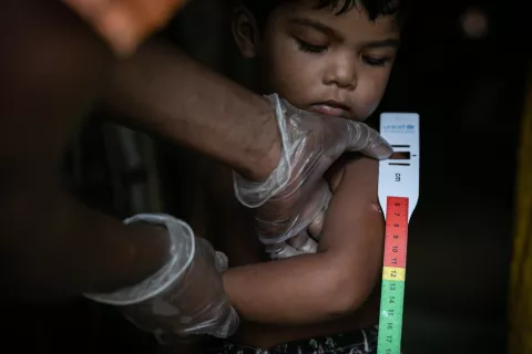 A Rohingya community volunteer measuring a child’s mid-upper arm circumference to screen for malnutrition