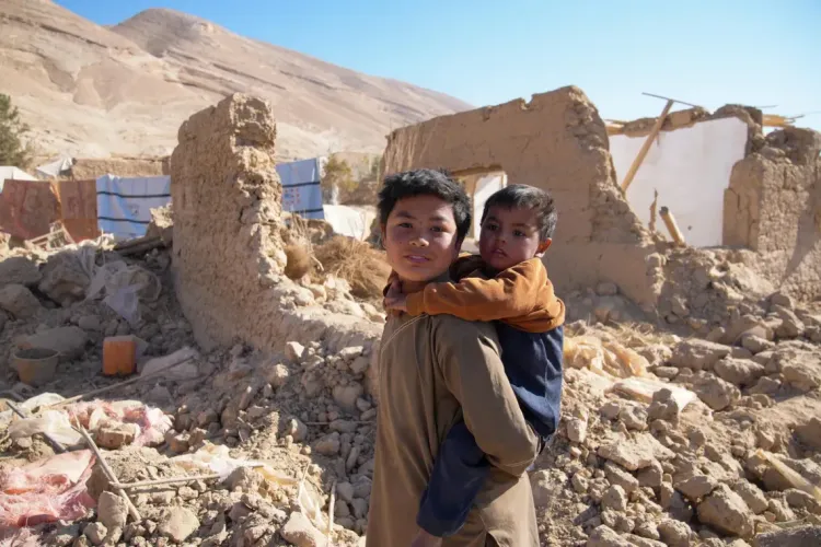 A boy carries his brother near the remains of their home in Samangan Province, Afghanistan.