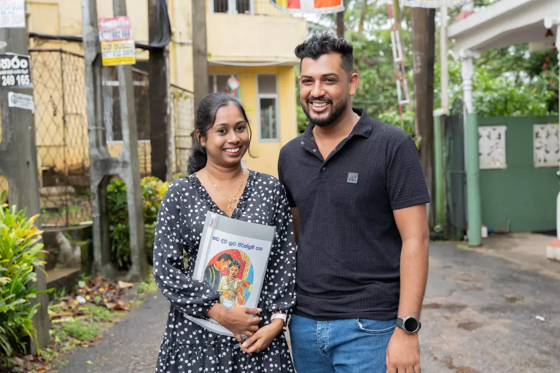 A newly married couple pose with a booklet on pre-pregnancy care after visiting a medical facility