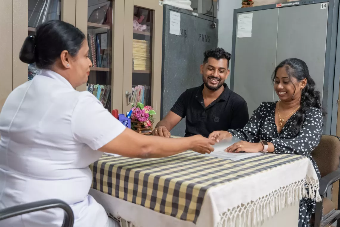 A newly married couple receiving guidance on pre-pregnancy care from a nurse