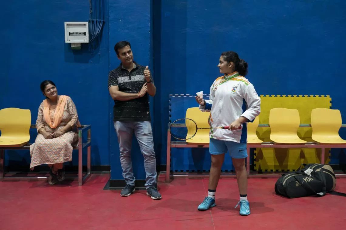 Gaurav Sharma, the father of Gauranshi Sharma, gestures to her as her mother watches them during a training session