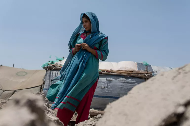 Noor Khatoon, 22, in front of her destroyed house