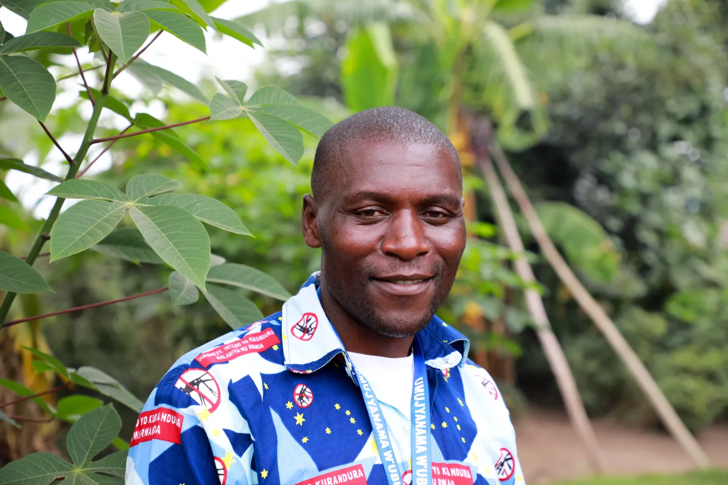 Daniel, a community health worker in Rwanda, smiles outside a house he visited to discuss Ebola prevention.