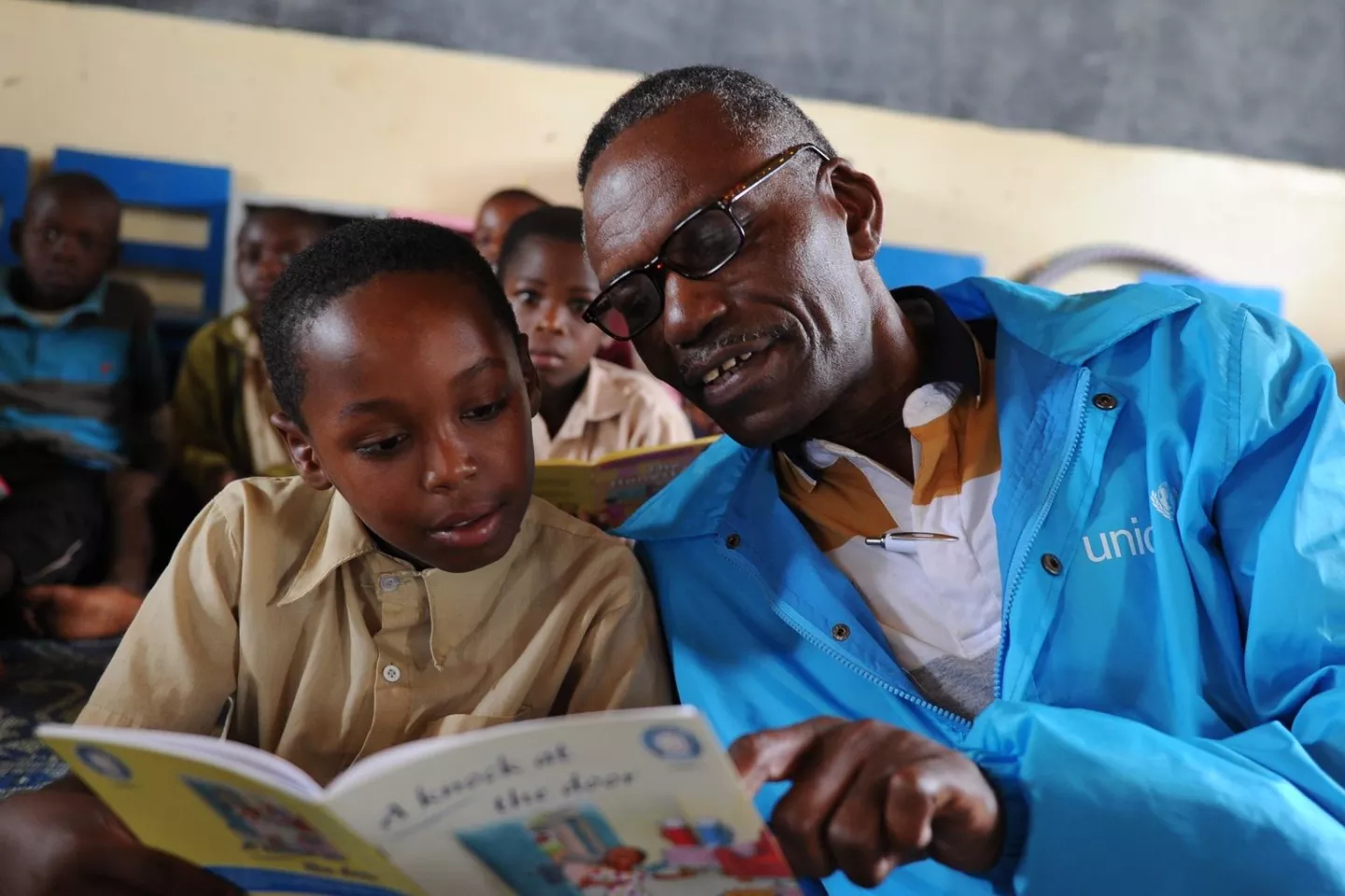 Cyriaque Ngoboka, UNICEF Communication Specialist, reads a book with a young boy at a primary school in Rwanda.