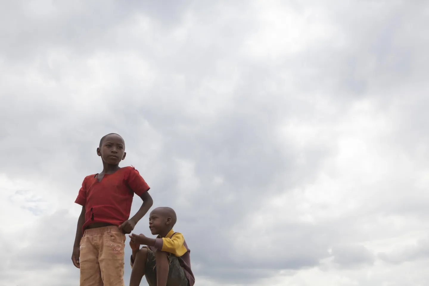 Two Burundian refugee boys survey Mahama Camp from atop a mound of dirt. 