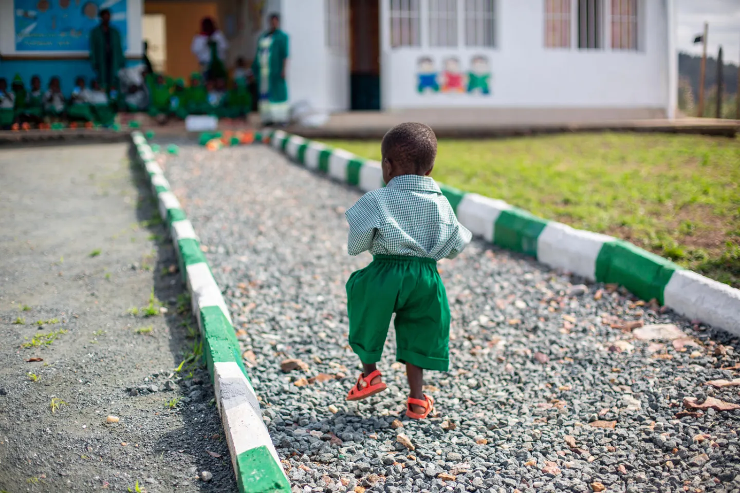 At the Rutsiro Tea Plantation early childhood development centre, David walks slowly back towards his friends while they drink milk.