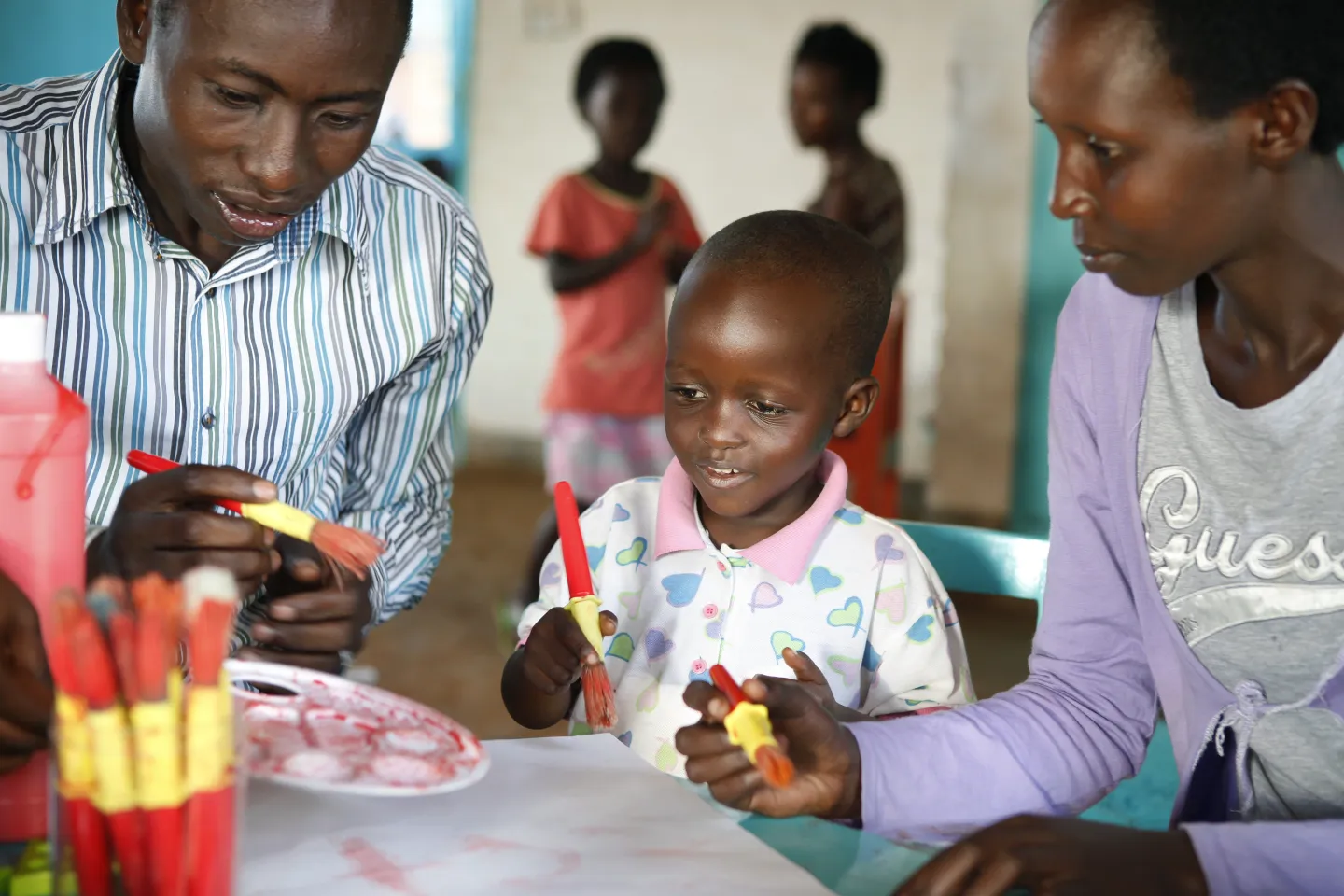 Child with male and female teacher / caregiver at an early childhood center in Rwanda