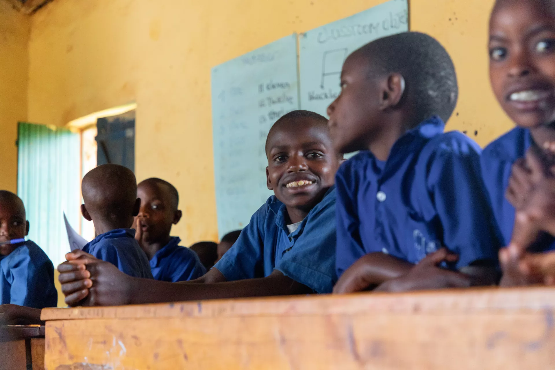 Hodari, centre, sits with fellow primary students in his classroom in Rwanda. Hodari learns under a UNICEF supported inclusive education programme to integrate children with disabilities in regular classrooms.