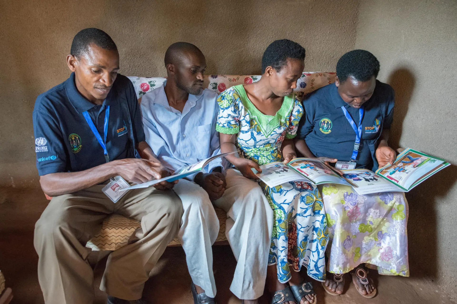 One of Rwanda's "Friends of the Family" child protection volunteers visits a family in Rwamagana District and reads some educational materials with the parents. 
