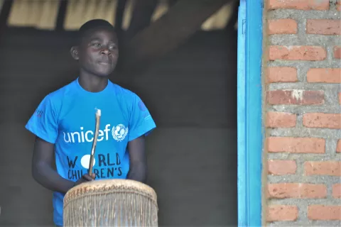 Child in Rwanda on World Children's Day plays the drums wearing a UNICEF shirt.