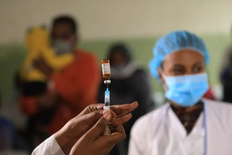 A doctor prepares to administer a vaccine dose as a nurse look on