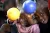 Two preschool children in Rwanda hold balls and small at camera