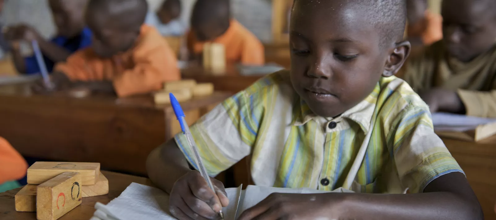 Boy student in Rwanda classroom writes in book