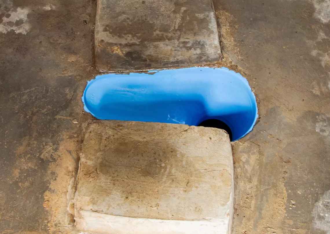 A blue plastic latrine toilet seal.