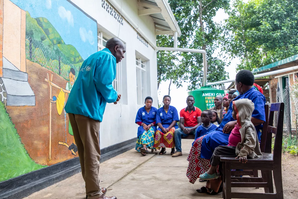UNICEF's Jean Claude Hagumimana engages parents in a discussion on hygiene and handwashing, using the child care centre's new mural as a visual guide.