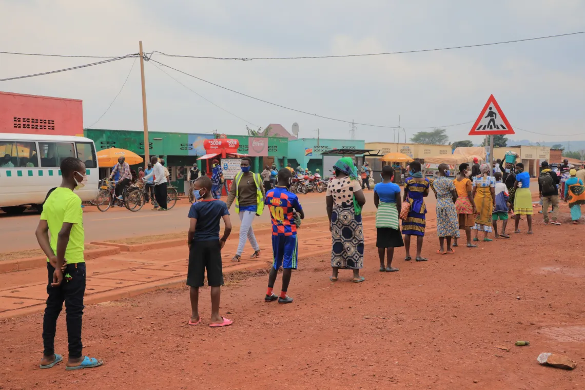 Marketgoers in Kirehe, Rwanda queue while practicing physical distancing, a COVID-19 prevention measure encouraged by UNICEF's risk communication and community engagement consultants.