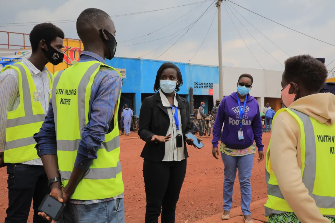 Odette Mpungirehe, a UNICEF consultant conducting risk communication and community engagement activities to fight COVID-19, briefs youth volunteers near the market in Kirehe District, Rwanda.