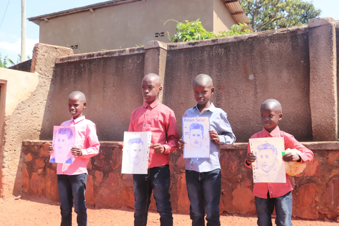 Manzi and his new brothers show off drawings of their favourite professional football players.