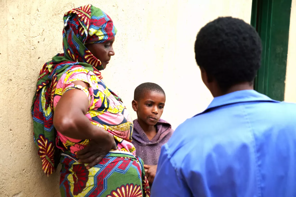 A child and two women standing together in conversation.