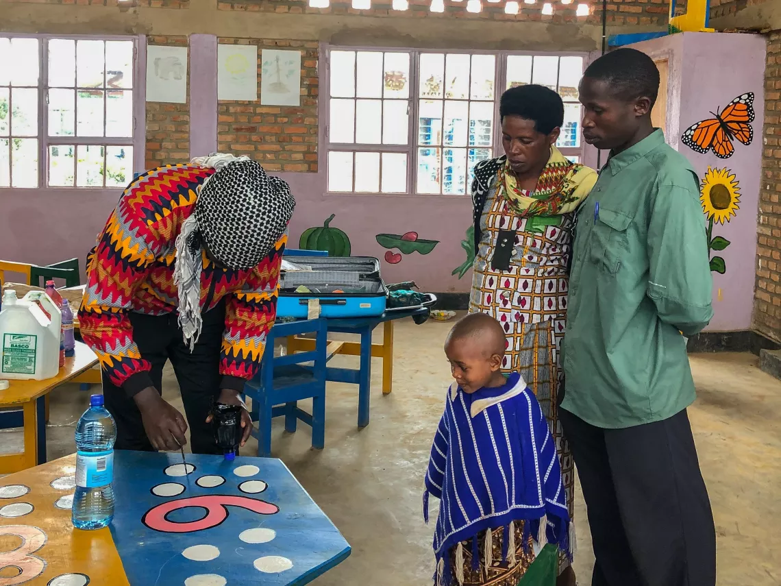 At the Gicumbi District Model Early Childhood Development Centre supported by UNICEF, Timothy paints numbers on the children's classroom tables.