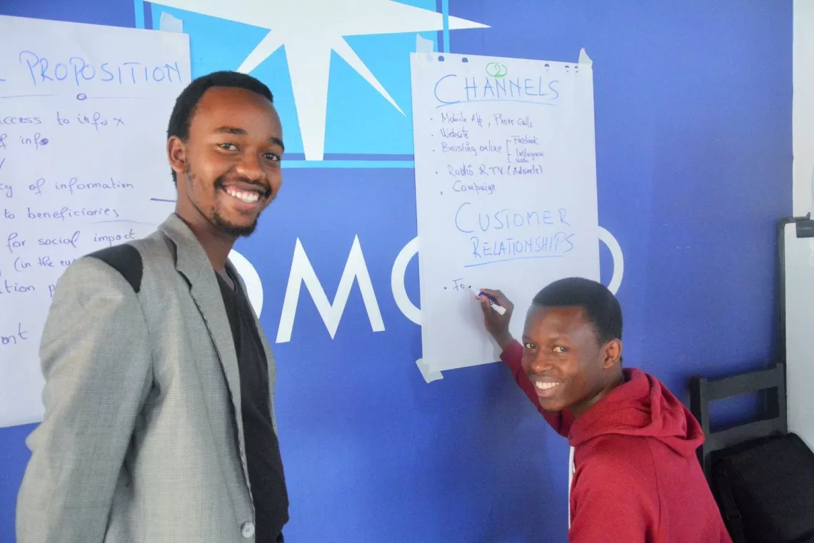 Two young boys in Rwanda write on flip chart paper