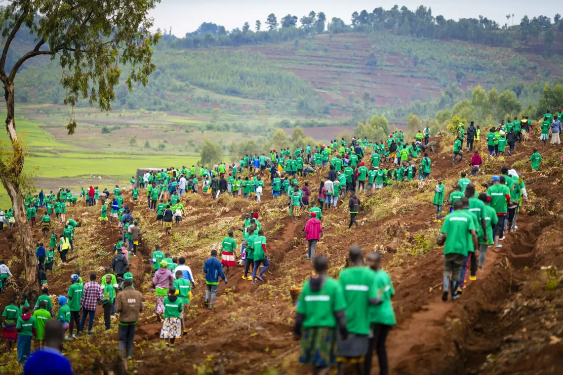 Many people wearing green clothes spread out on a hill.