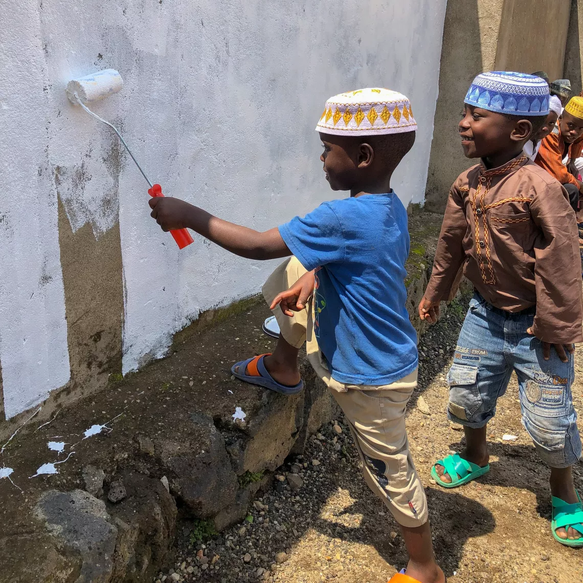 In Rubavu District, two boys at the Madjengo Early Childhood Development Centre help paint the wall white in preparation for a new mural.