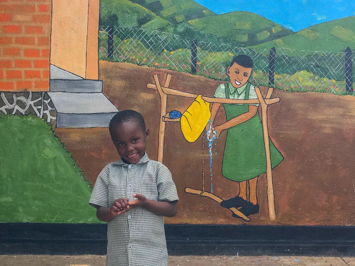 Honorine, 5, stands in front of a new mural at her early childhood development centre supported by UNICEF, which depicts good handwashing and hygiene behaviour.