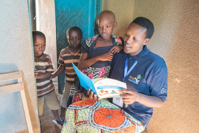 Woman with children in Rwanda reads education materials on violence against children