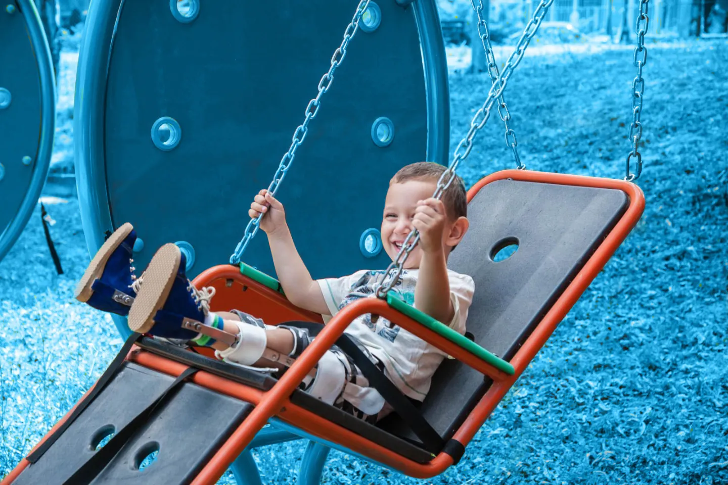 Boy with disability swings in a swing for disabled children