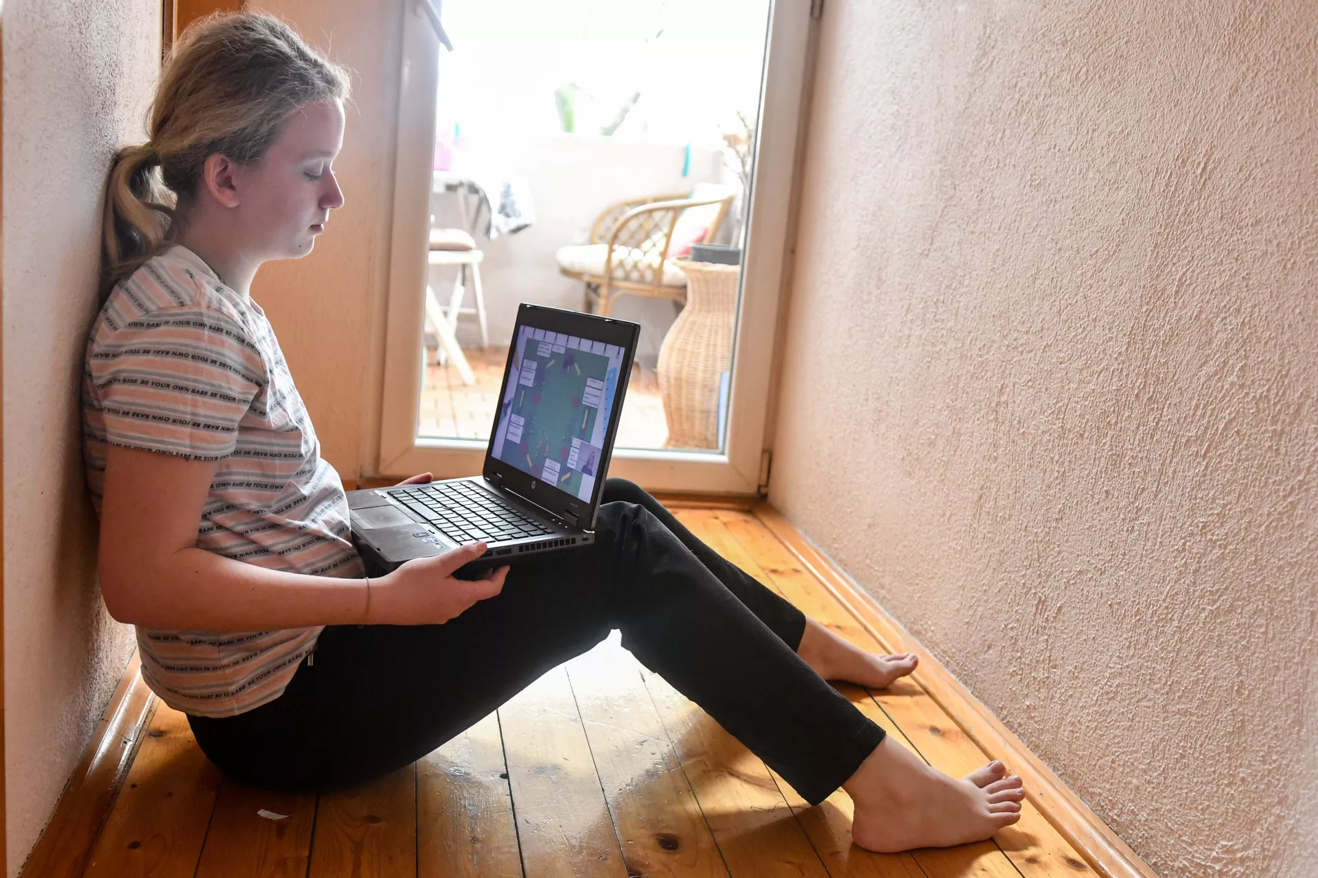 Devojčica uči na laptopu kod kuće