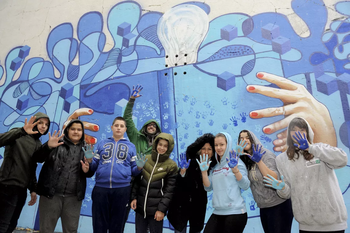 The school principal, Pijanista and pupils in front of the completed mural.