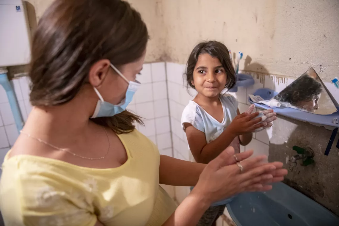 Marina teaching six-year-old Elena how to wash her hands properly.