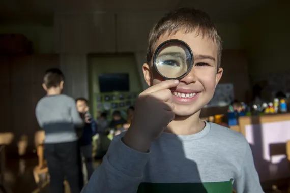 child in kindergarten with a magnifying glass