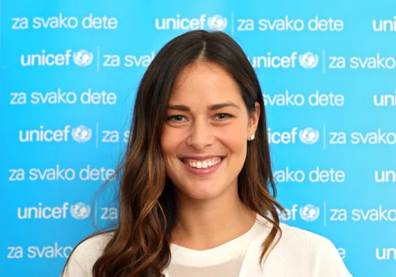 Ana Ivanovic smiling at the camera in front of the UNICEF banner