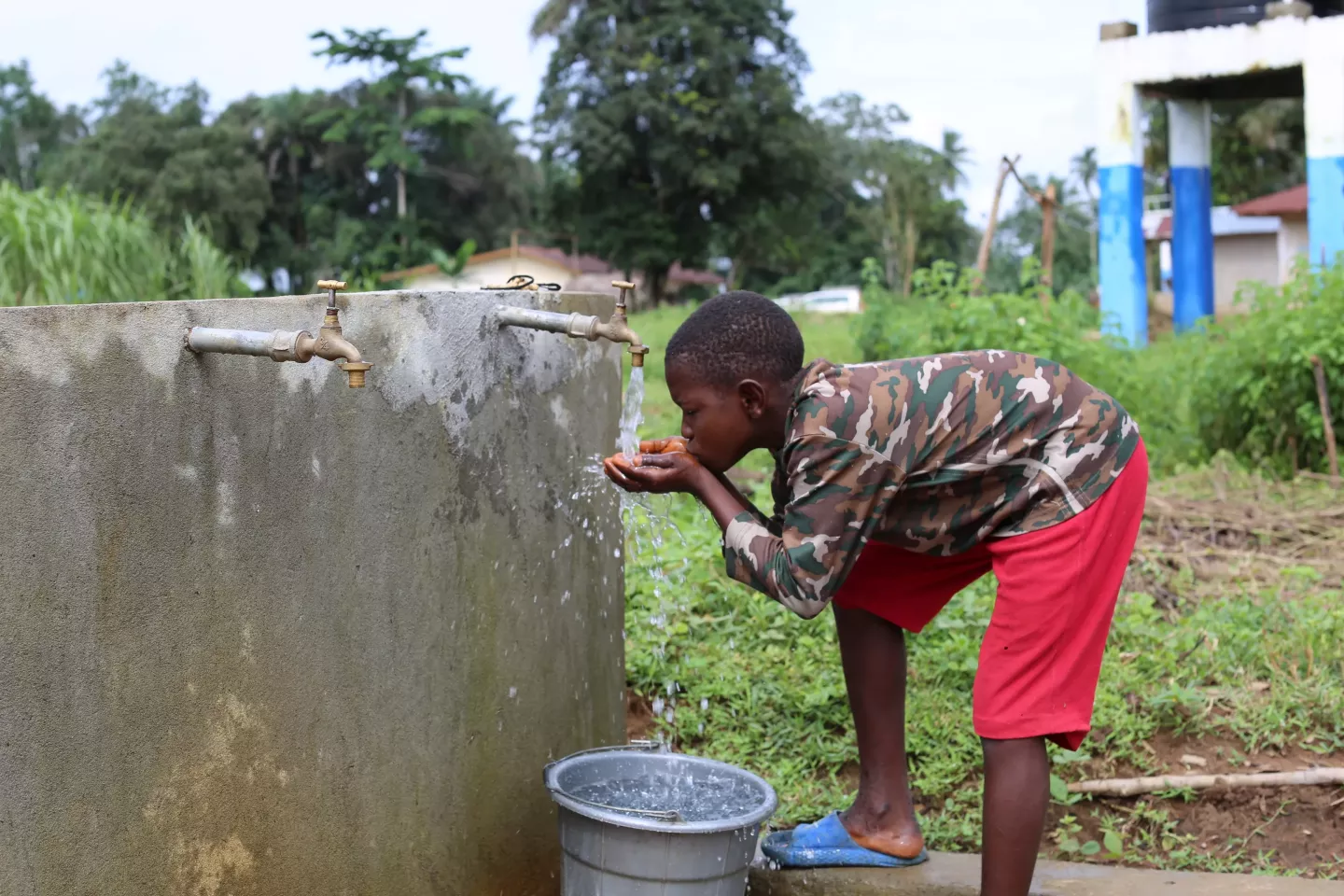 A boy drinks from a tap.
