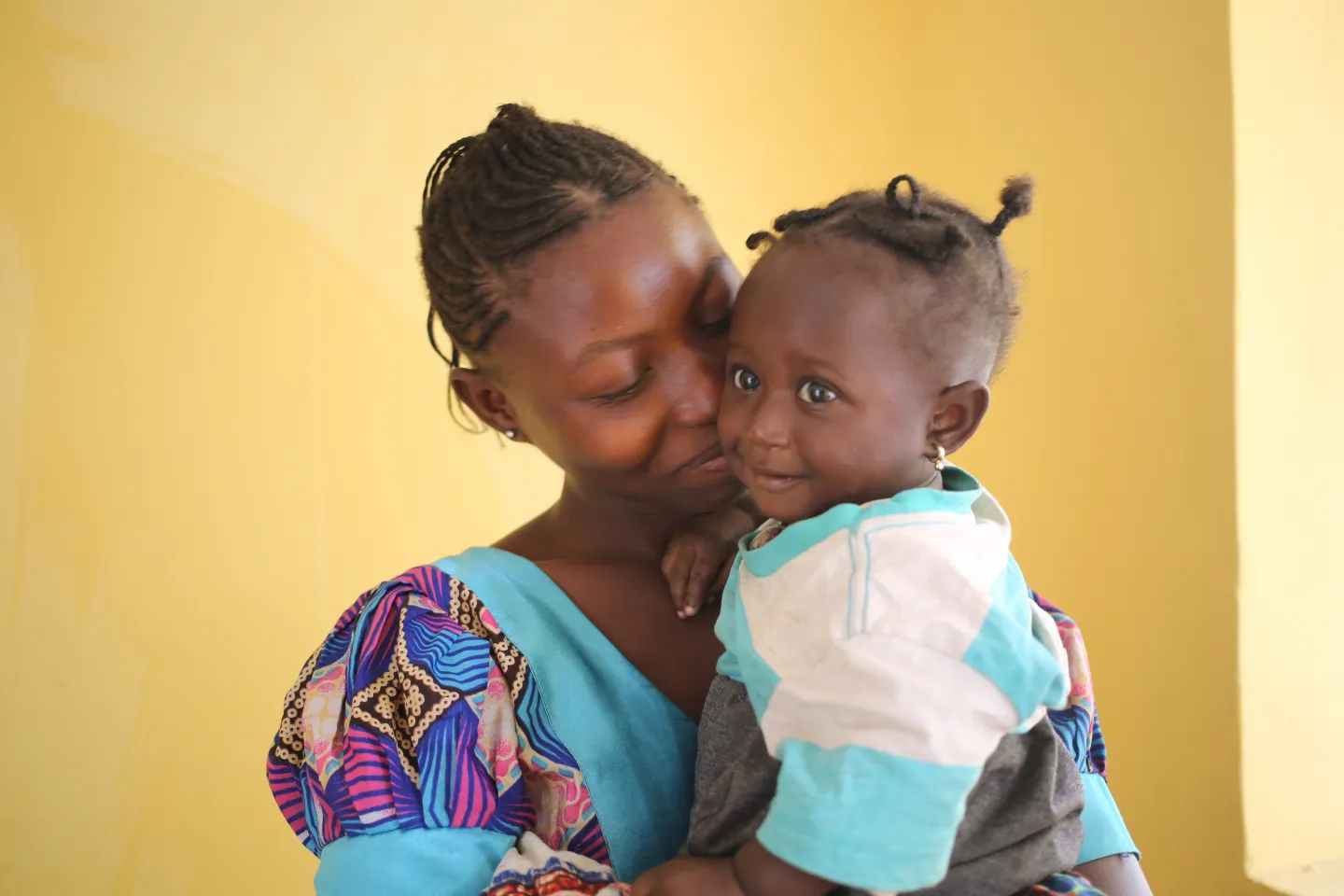 A woman carries her baby girl inside the Konsho Community Health Centre in Bombali district, northern Sierra Leone