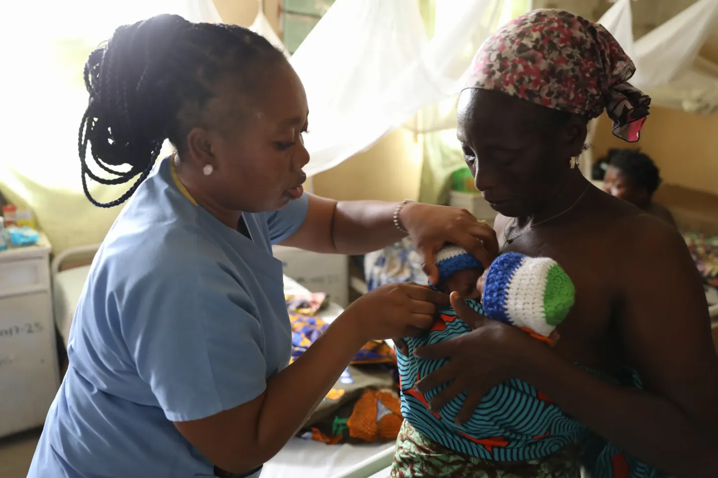 Nurse Sia Gborie, head nurse at the Special Care Baby Unit at the Bo Government Hospital, helps grandmother Hawa George to strap her twin grand babies to her chest so that she could practice Kangaroo Mothers Care on them