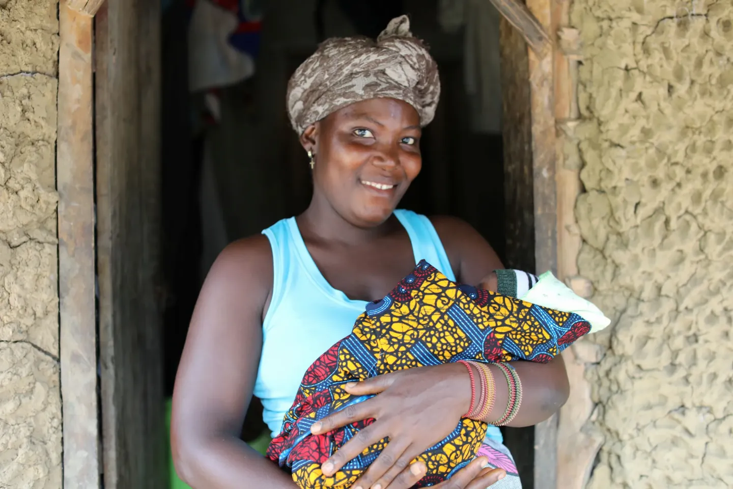 Hawa, 36, carries her newborn at their home in Kpatema, southern Sierra Leone.