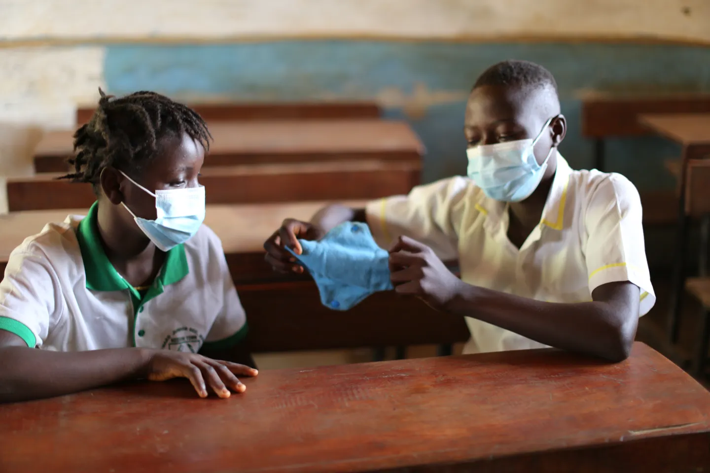 A boy and a girl sit and talk in a classroom
