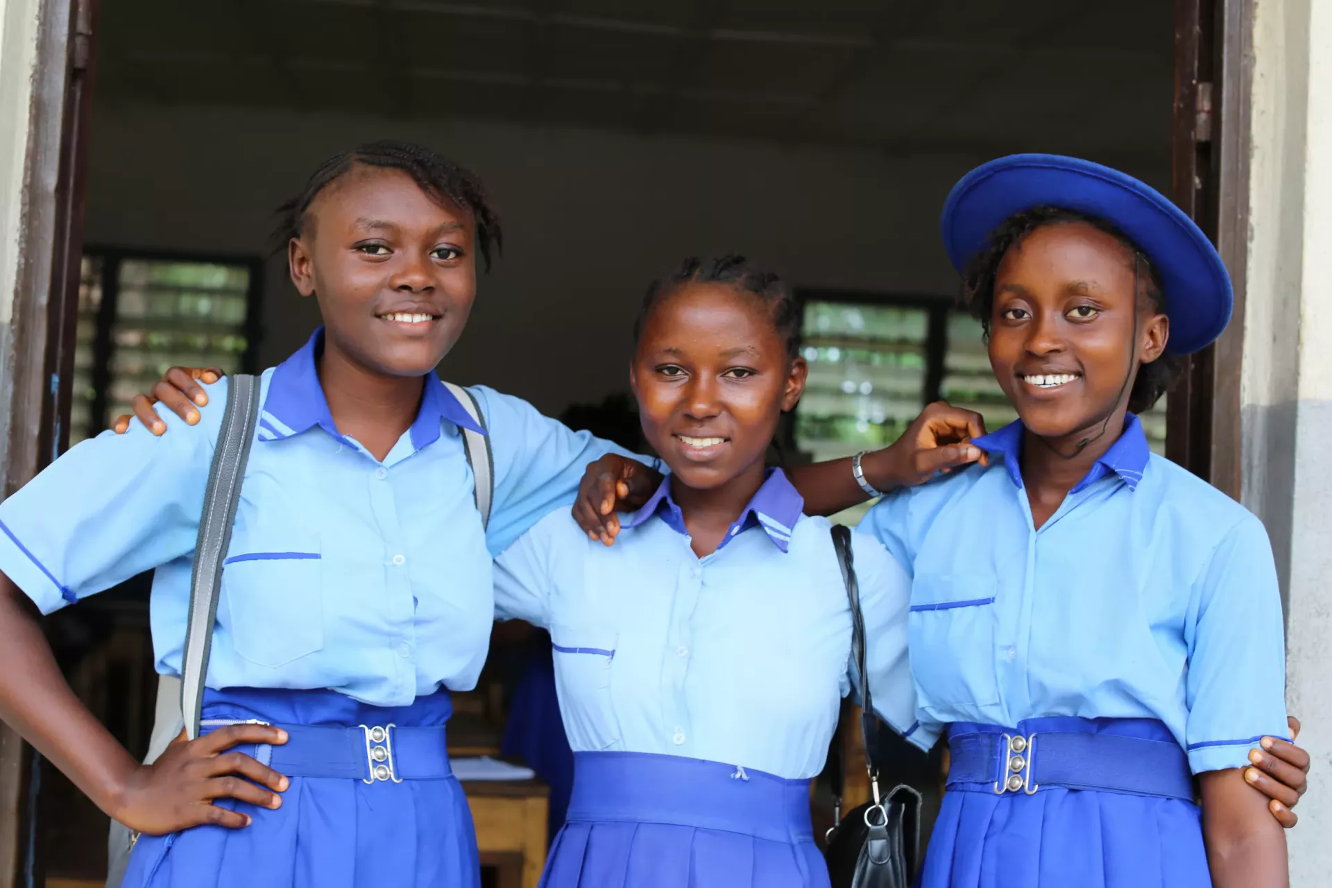 A group of adolescent schoolgirls stand by their classroom