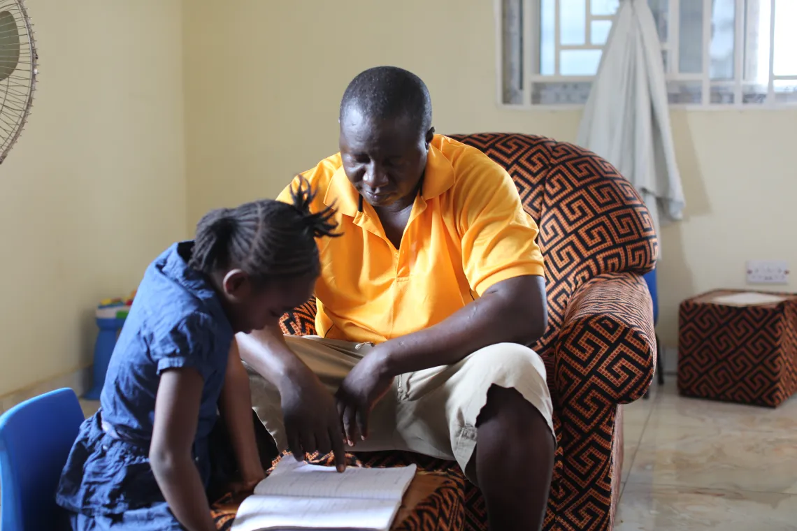 Yayah Bangura (a UNICEF staff) helps his 8-year-old daughter Isha with her schoolwork, at their home in Freetown.